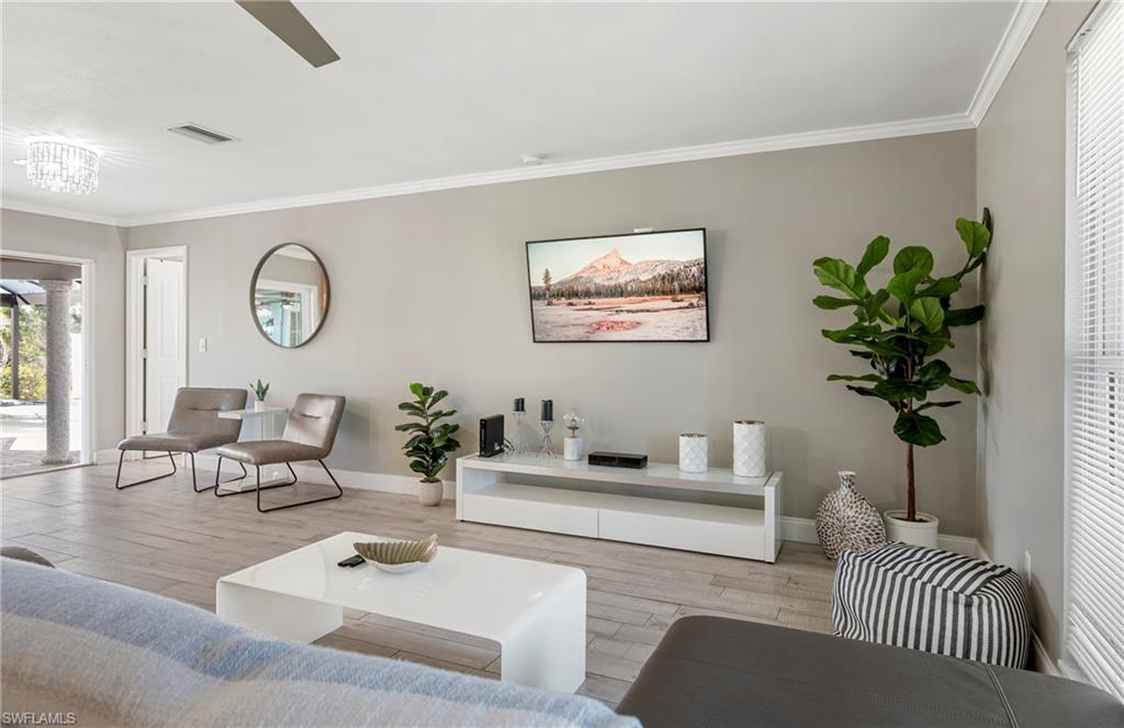 Living area with ornamental molding and wood finished floors
