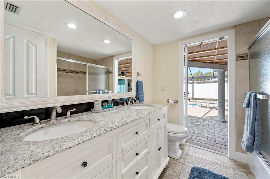 Bathroom with a tile shower, double vanity, recessed lighting, plenty of natural light, and light tile patterned flooring