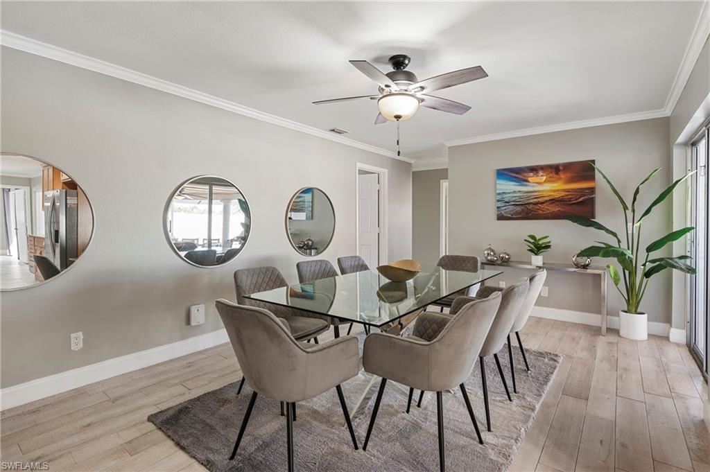 Dining area featuring light wood-style flooring, ornamental molding, a ceiling fan, and arched walkways