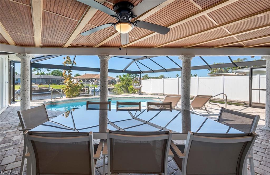 View of patio featuring a lanai, a sunroom, an outdoor pool, a ceiling fan, and a water view