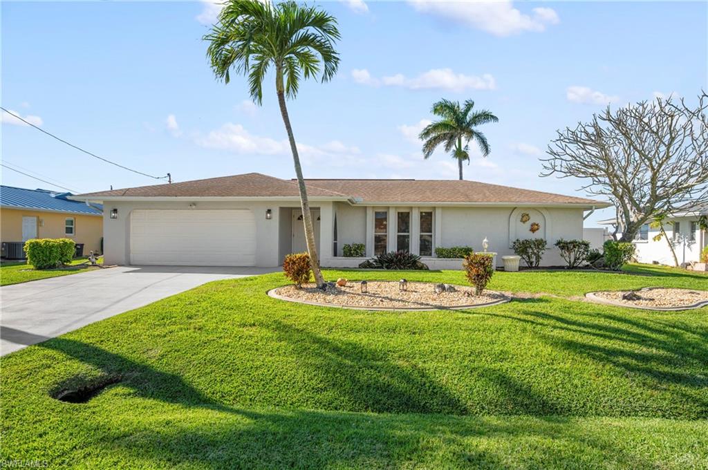 Ranch-style house with stucco siding, a front yard, driveway, and an attached garage
