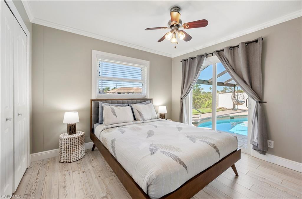 Bedroom featuring access to exterior, light wood-type flooring, crown molding, ceiling fan, and a closet