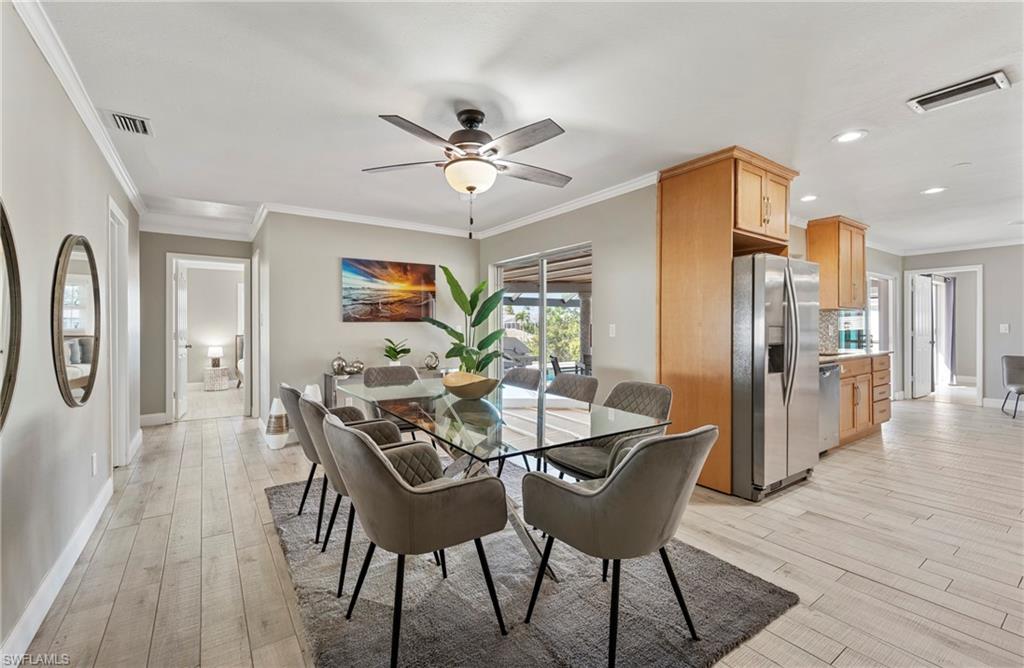 Dining area with ornamental molding, light wood-style flooring, and ceiling fan
