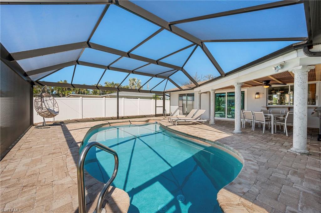 View of pool with glass enclosure, a patio area, a sunroom, and outdoor dining space