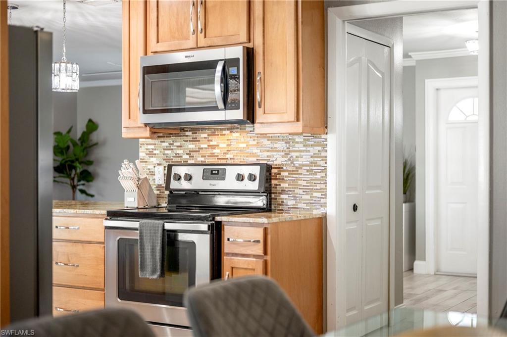 Kitchen with ornamental molding, stainless steel appliances, tasteful backsplash, and light stone countertops