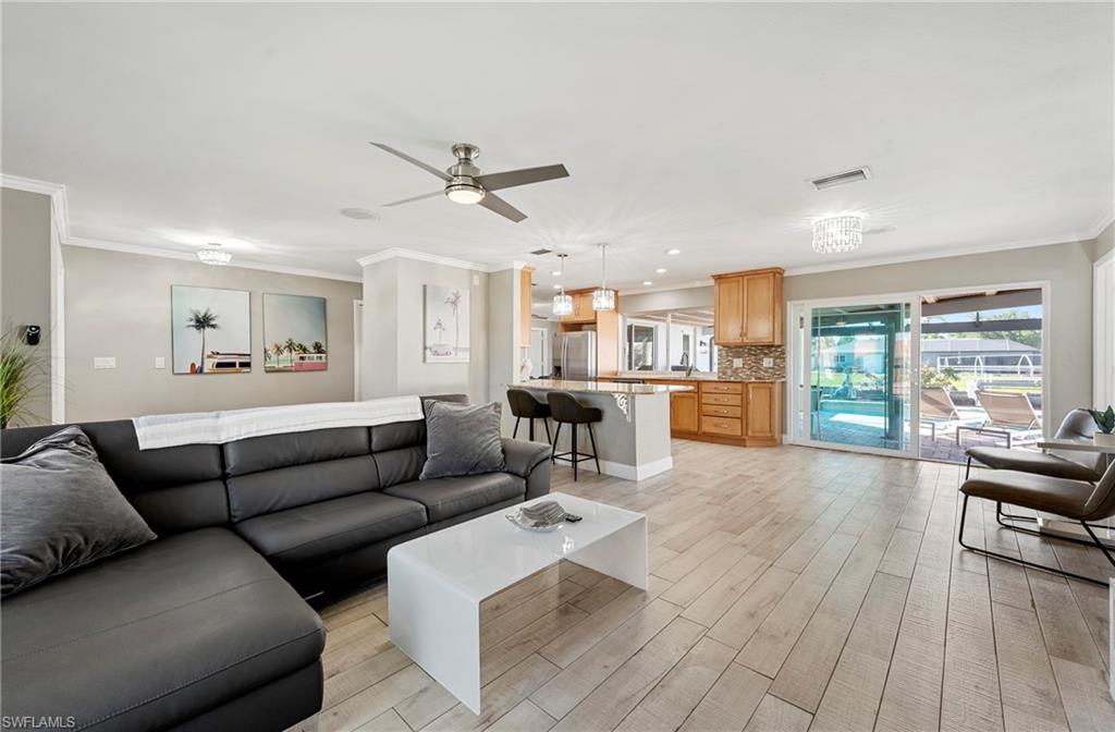Living room with crown molding, light wood finished floors, ceiling fan, and recessed lighting