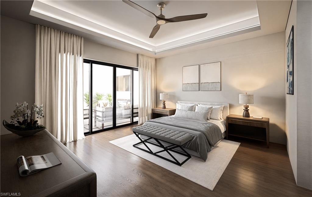 Bedroom featuring a tray ceiling, wood finished floors, and access to exterior