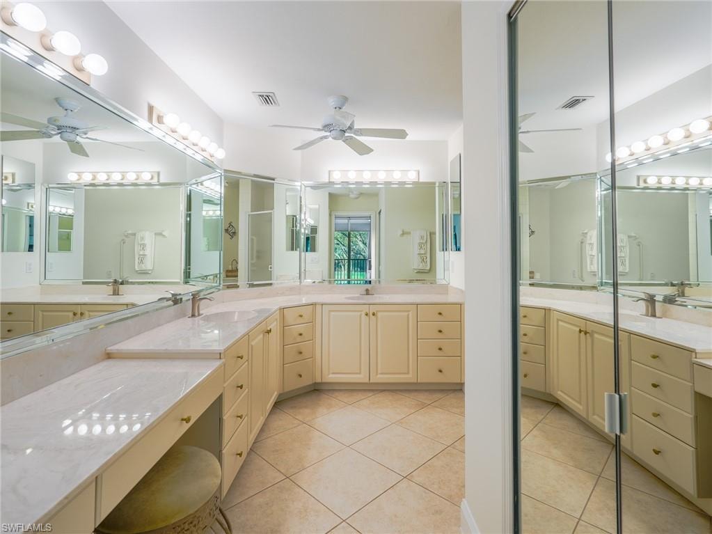 Full bathroom featuring two vanities, a ceiling fan, and light tile patterned floors
