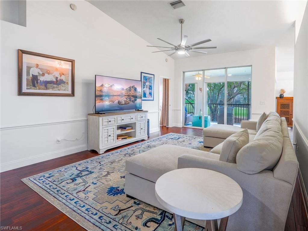 Living area featuring dark wood-type flooring, a ceiling fan, and vaulted ceiling