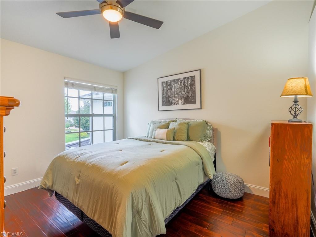 Bedroom with dark wood-style flooring, lofted ceiling, and a ceiling fan