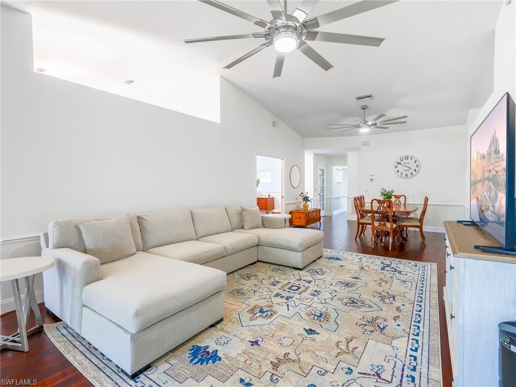 Living area featuring dark wood-type flooring, vaulted ceiling, and a ceiling fan