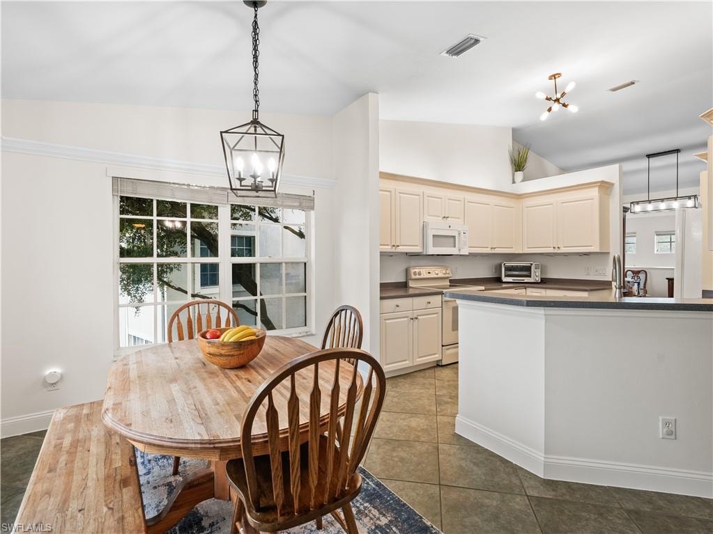Dining space with a chandelier, light tile patterned floors, and lofted ceiling