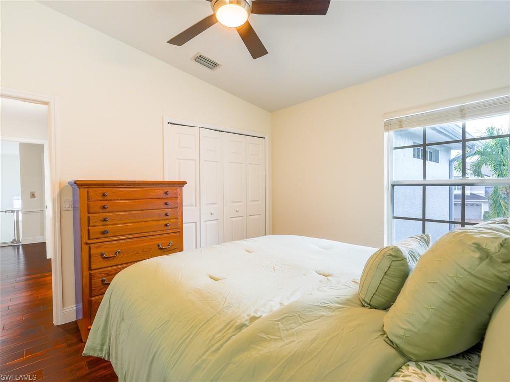 Bedroom with lofted ceiling, a closet, dark wood-style floors, and ceiling fan