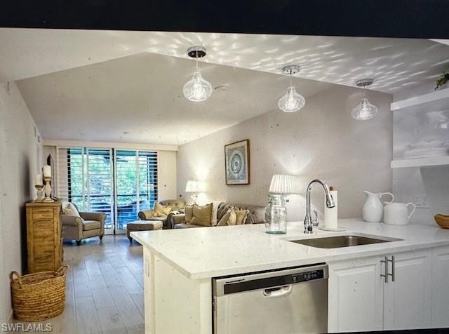 Kitchen with dishwasher, pendant lighting, light stone counters, white cabinetry, and a peninsula