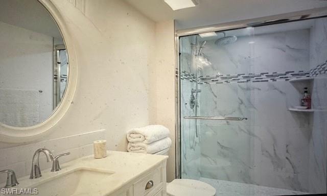 Bathroom featuring vanity and a marble finish shower