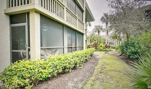 View of property exterior featuring stucco siding, a sunroom, and a balcony