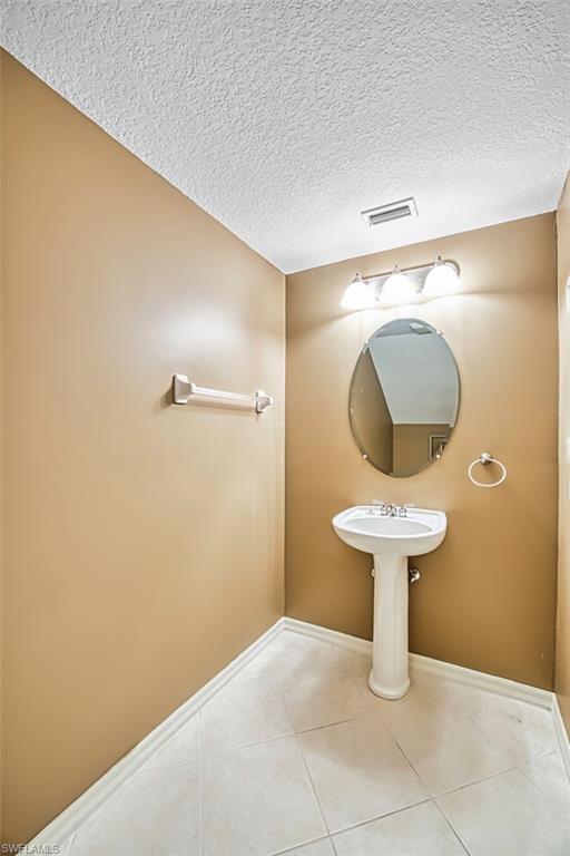 Half bathroom featuring a textured ceiling and light tile patterned flooring