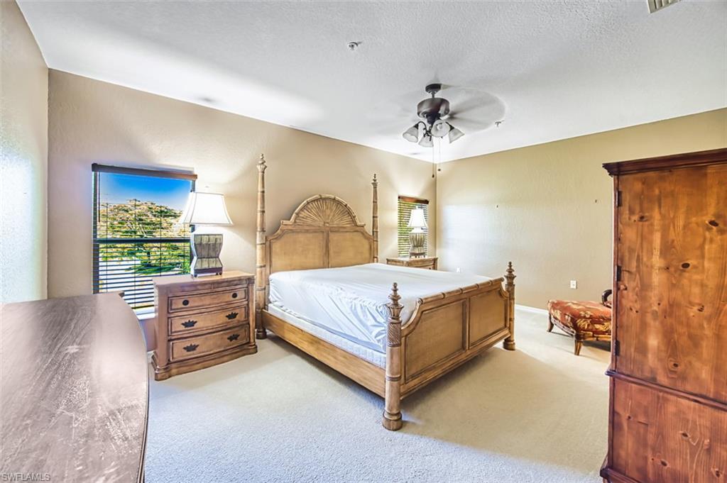 Carpeted bedroom featuring a ceiling fan and a textured ceiling