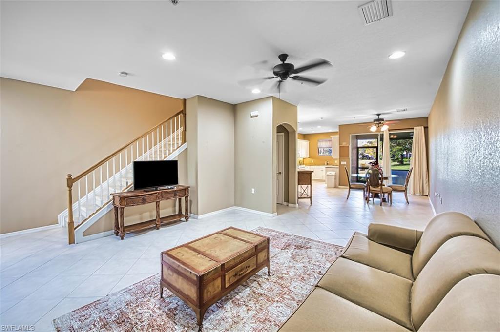Living area featuring tile patterned flooring, recessed lighting, stairway, ceiling fan, and arched walkways