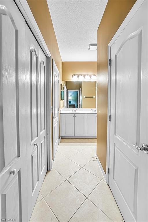 Corridor featuring a textured ceiling and light tile patterned flooring