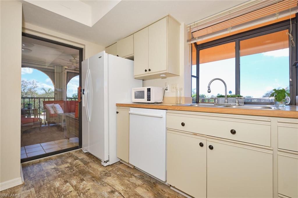 Kitchen with cream cabinets, white appliances, and light wood-type flooring