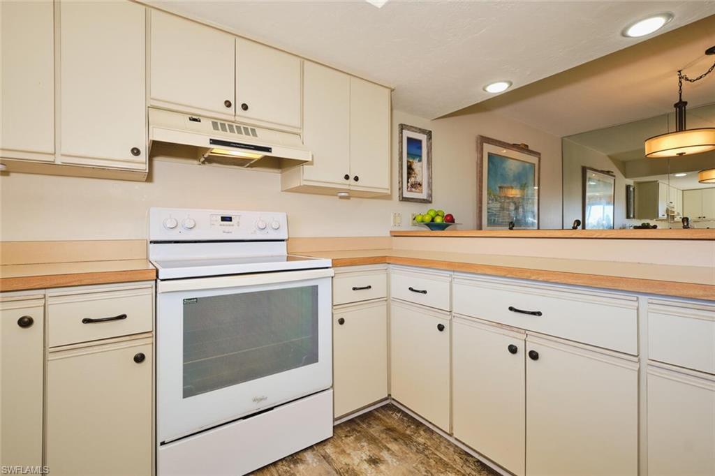 Kitchen featuring electric range, light countertops, under cabinet range hood, light wood-style flooring, and recessed lighting