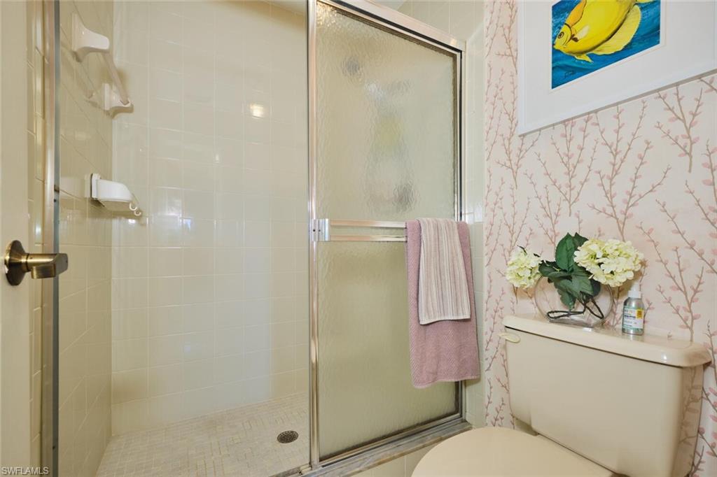 Bathroom with a stall shower and wallpapered walls