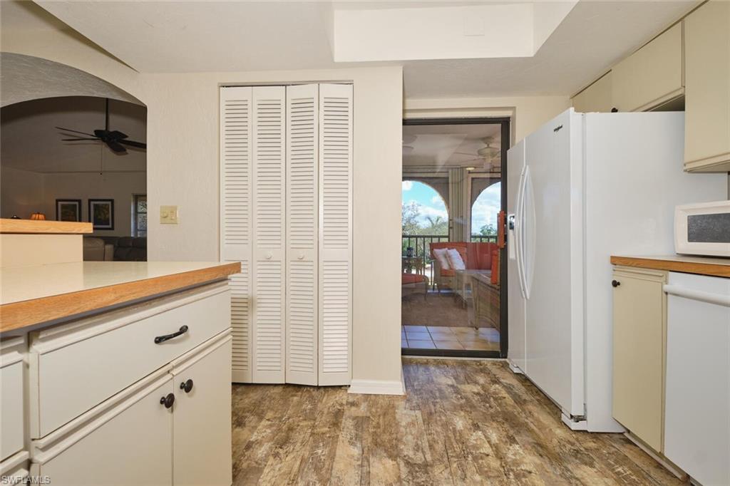 Kitchen with light countertops, cream cabinetry, white appliances, and dark wood finished floors