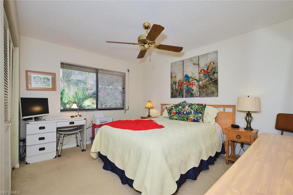 Carpeted bedroom featuring ceiling fan and a desk