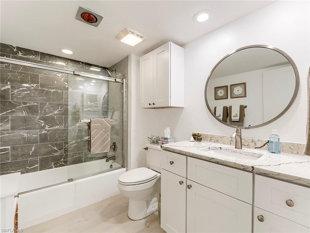 Full bathroom with vanity, shower / bath combination with glass door, light wood-style floors, and recessed lighting