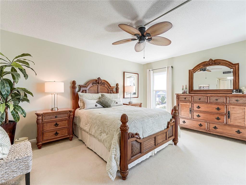 Bedroom featuring light carpet, ceiling fan, and a textured ceiling