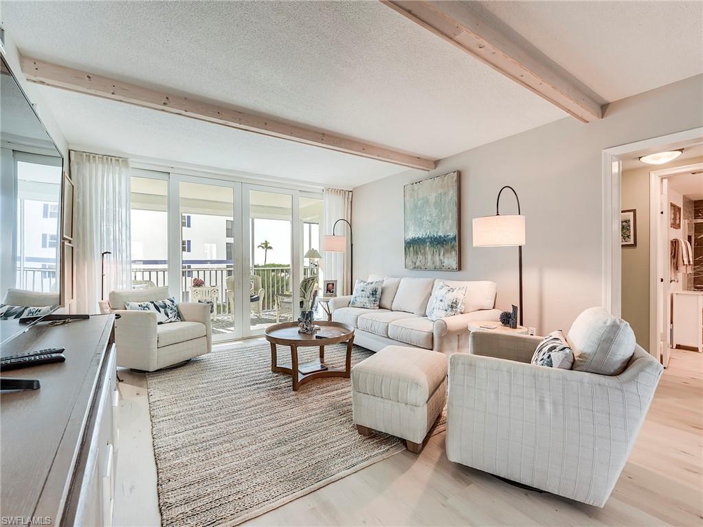 Living room featuring beam ceiling, a textured ceiling, and light wood-style flooring