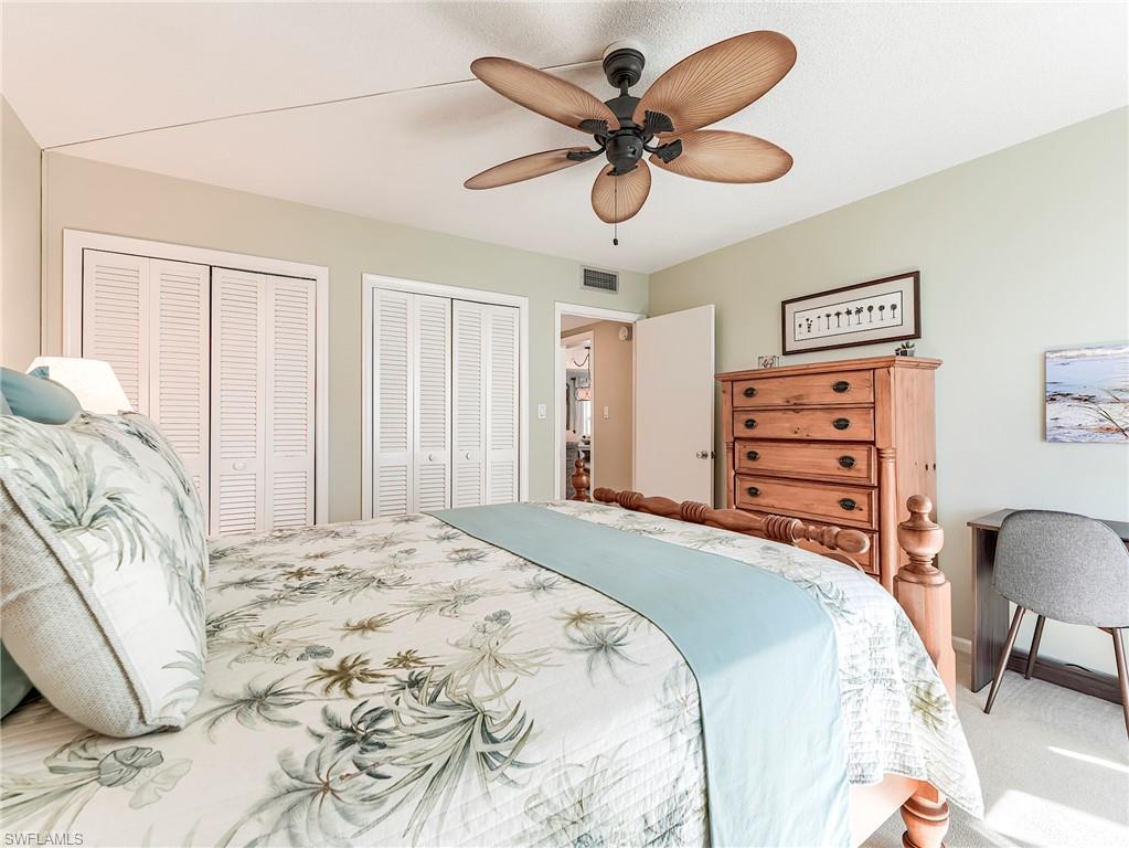 Carpeted bedroom featuring two closets and ceiling fan