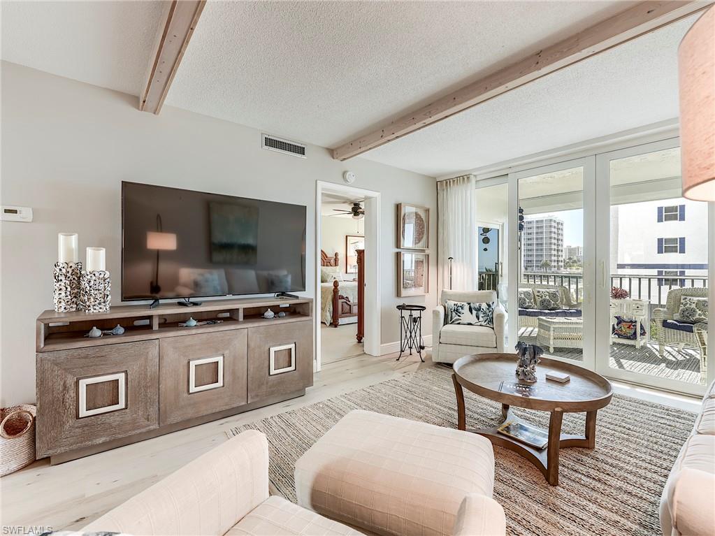 Living room with a textured ceiling, beamed ceiling, and wood finished floors