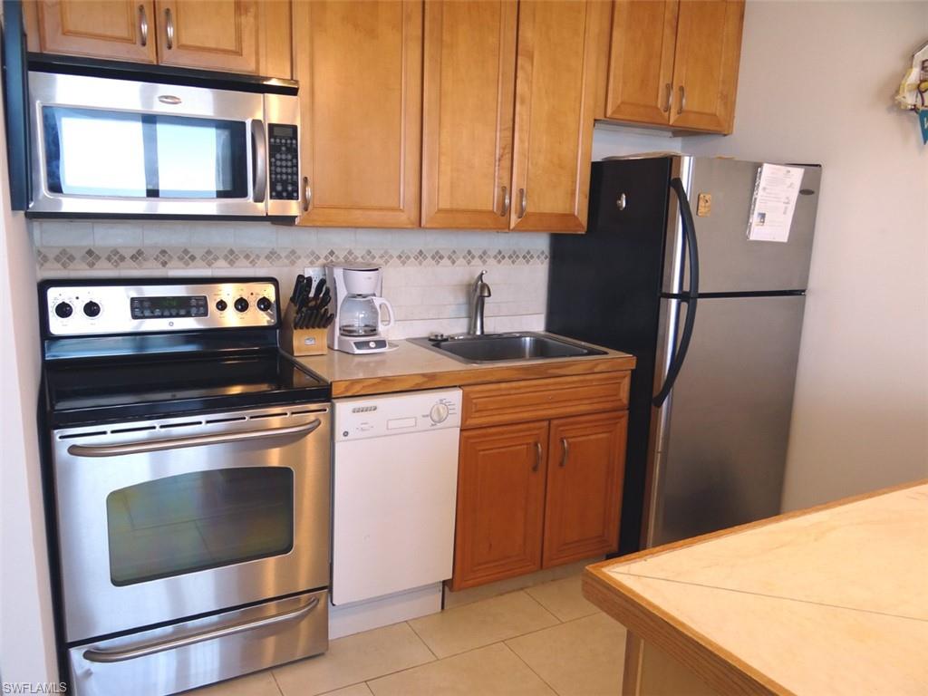Kitchen featuring stainless steel appliances, tasteful backsplash, brown cabinets, and light tile patterned flooring