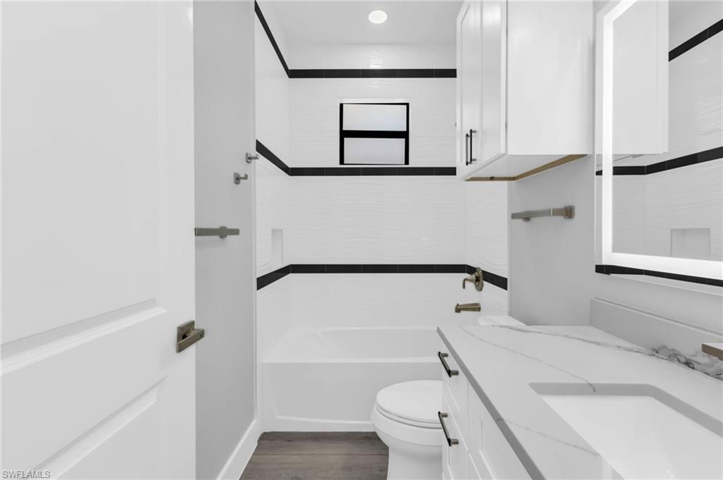 Full bathroom with vanity, dark wood-style flooring, and bathing tub / shower combination