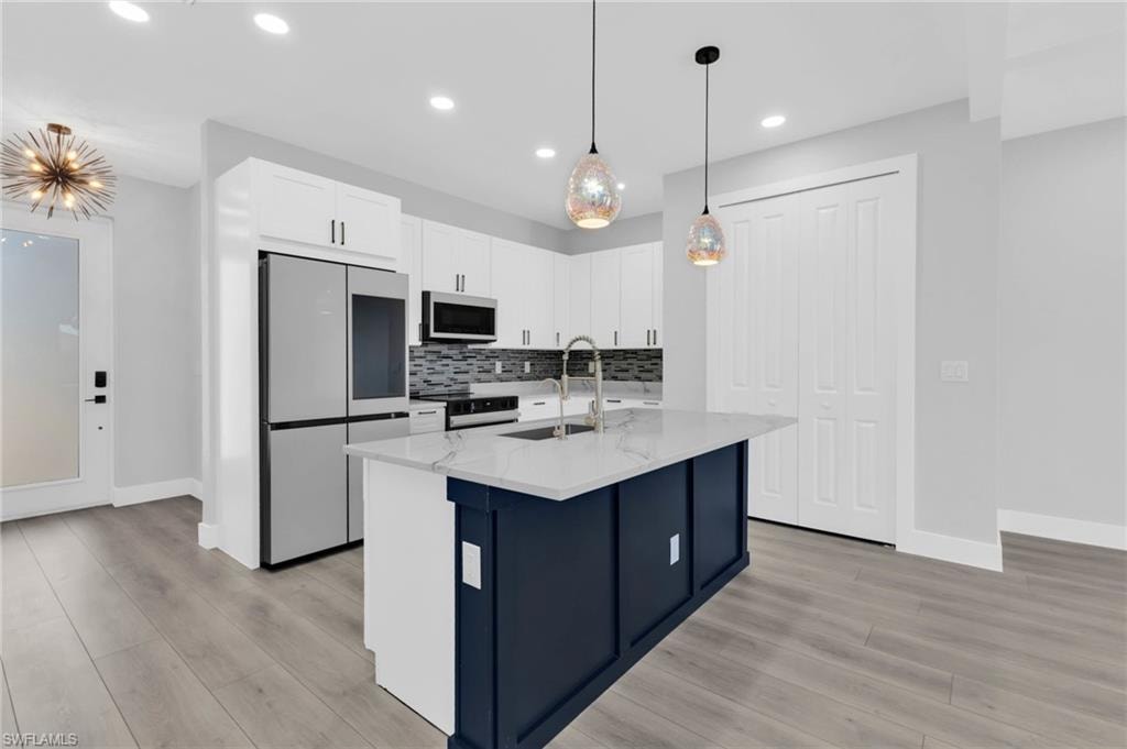 Kitchen with smart refrigerator, white cabinets, light stone counters, pendant lighting, and decorative backsplash