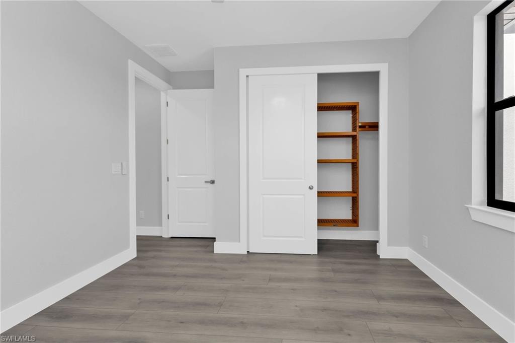Unfurnished bedroom with wood finished floors and a closet
