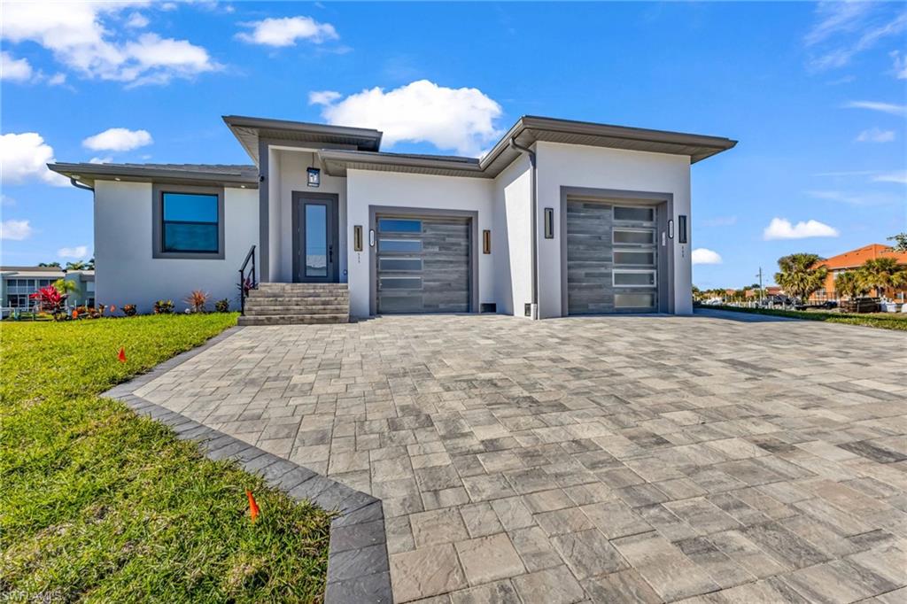 View of front of home featuring stucco siding, an attached garage, decorative driveway, and a front lawn