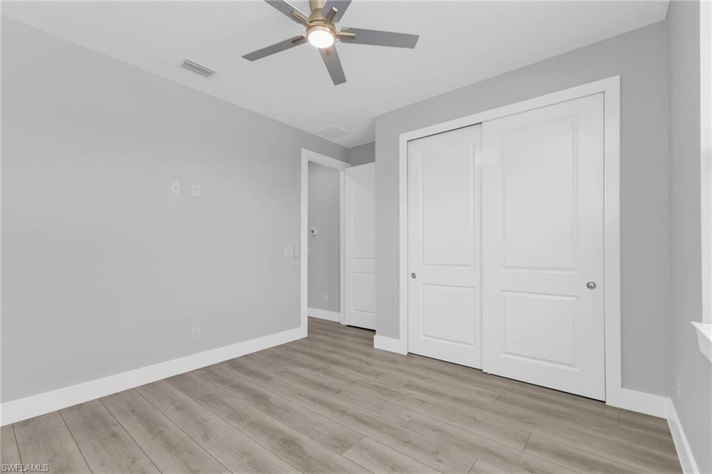 Unfurnished bedroom with light wood-style flooring, a ceiling fan, and a closet