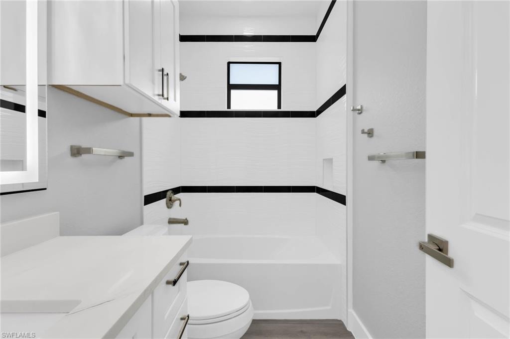 Bathroom featuring vanity, shower / washtub combination, and light wood-style flooring