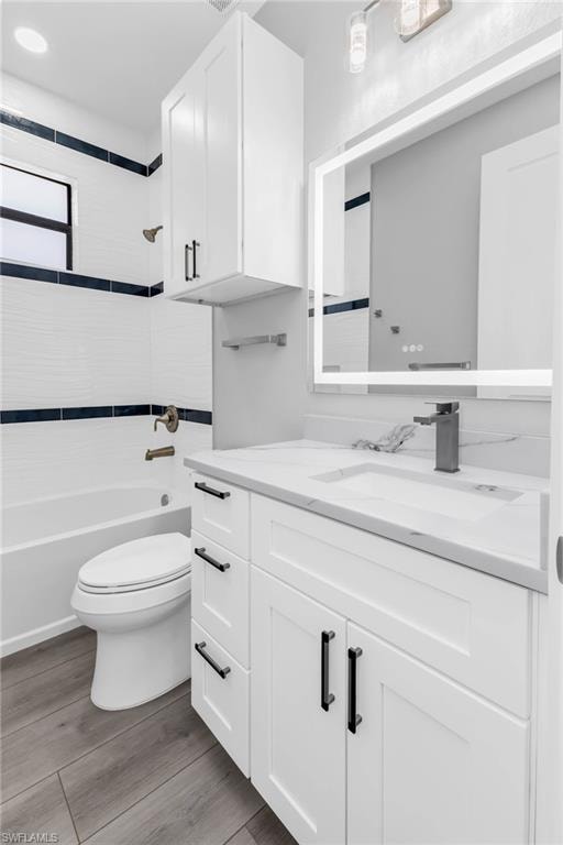 Full bath with vanity, bathing tub / shower combination, and light wood-style flooring