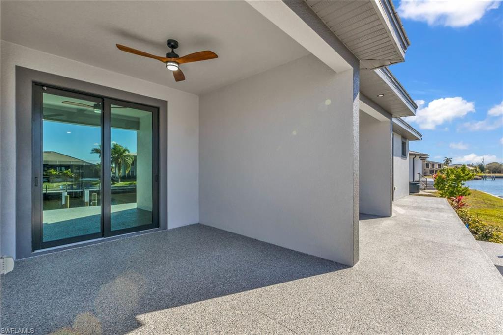 Property entrance with a water view, ceiling fan, a patio, and stucco siding