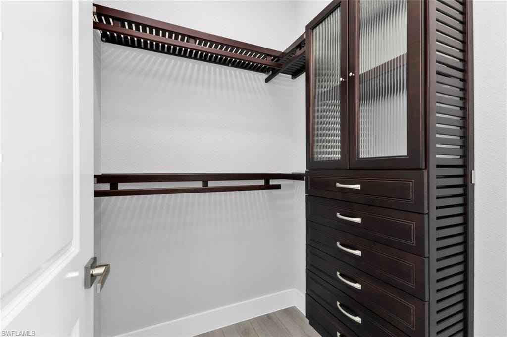 Walk in closet with light wood finished floors