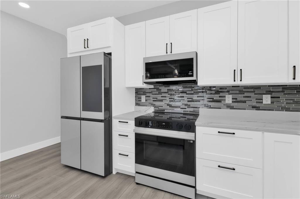 Kitchen featuring range with electric stovetop, smart refrigerator, tasteful backsplash, white cabinets, and light stone countertops