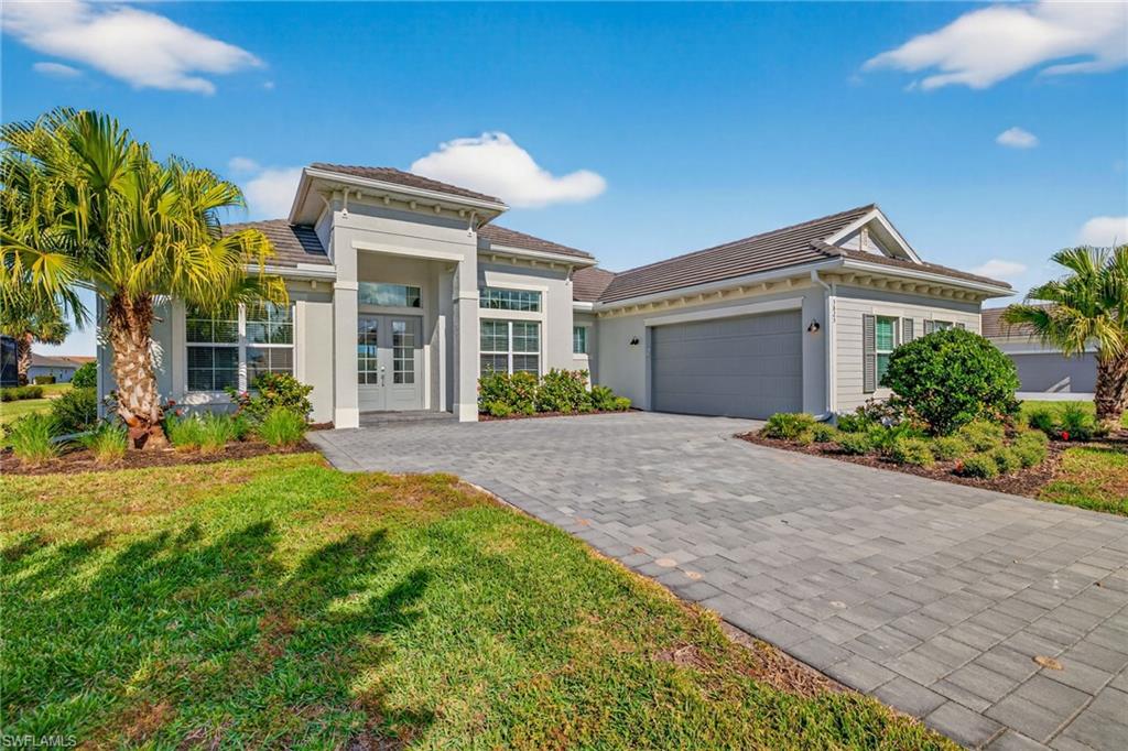 View of front of house featuring an attached garage, decorative driveway, stucco siding, and a front lawn