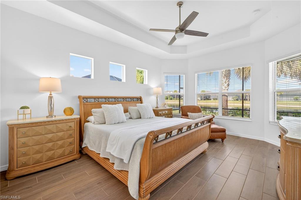 Bedroom with a raised ceiling, a ceiling fan, and wood tiled floors