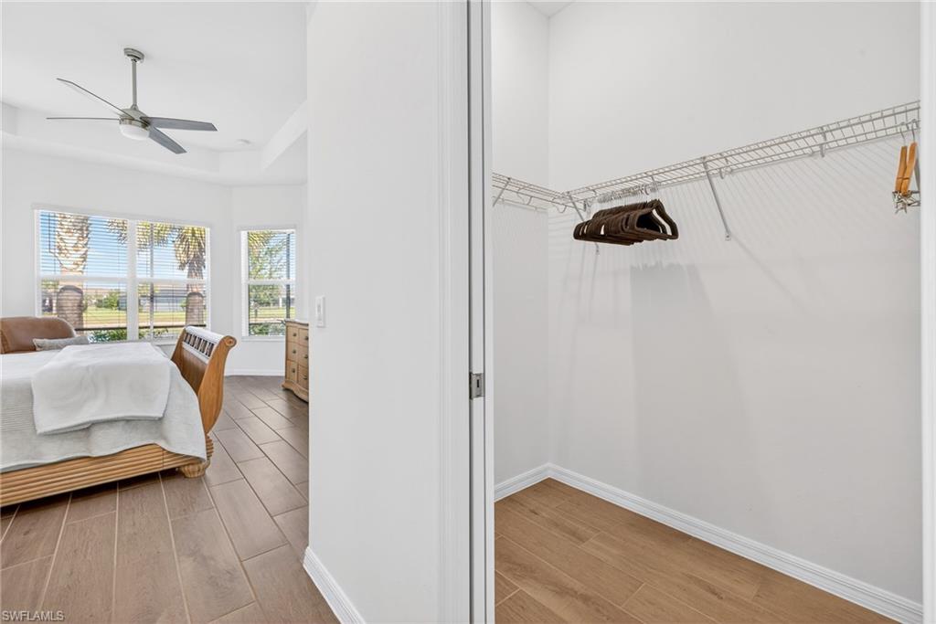 Bedroom featuring wood finish floors, a raised ceiling, and a ceiling fan