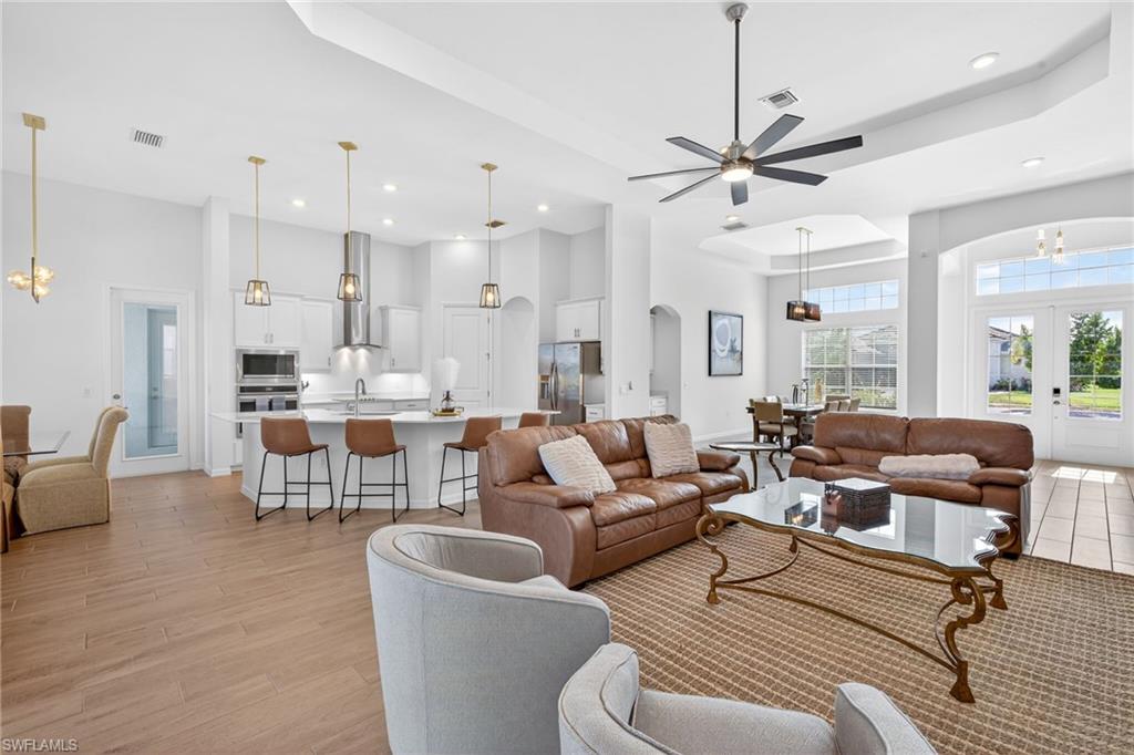 Living room with a chandelier, a tray ceiling, arched walkways, french doors, and a high ceiling