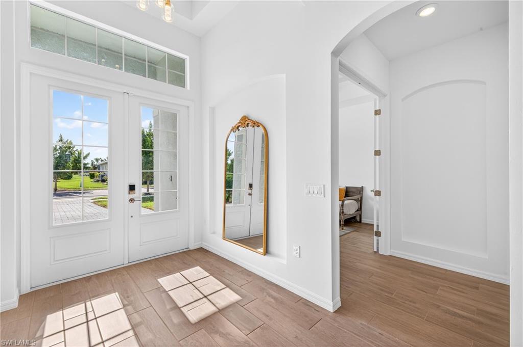 Foyer entrance with wood finished floors, arched walkways, and a towering ceiling